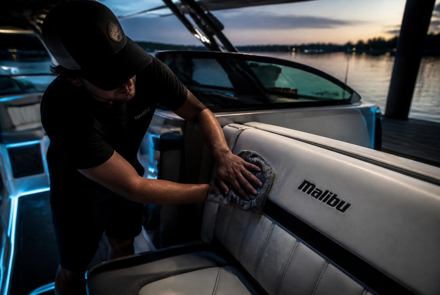 Detailer cleaning white vinyl boat seats aboard a wake boat at Lake Travis, TX